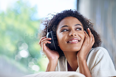 Buy stock photo Shot of a young woman wearing headphones listening to music at home