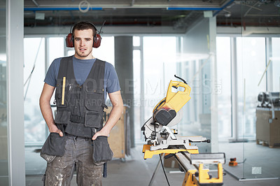 Buy stock photo Portrait of one young building contractor wearing noise cancelling headphone earmuffs while working on industrial architecture project at construction site. Engineer using power saw tools to renovate