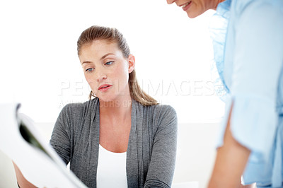 Buy stock photo A young businesswoman showing her colleague a document