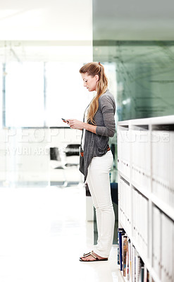 Buy stock photo Full-length shot of an attractive young businesswoman communicating with her mobile phone indoors
