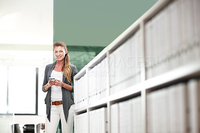 Buy stock photo Portrait of an attractive young businesswoman standing and holding a mobile phone