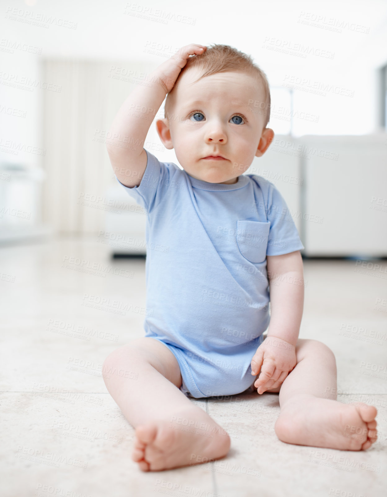 Buy stock photo A cute baby boy sitting on the living room floor scratching his head