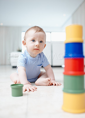 Buy stock photo A cute baby boy playing with his toys on the living room floor