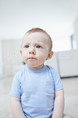 Buy stock photo A cute little baby boy frowning in the living room