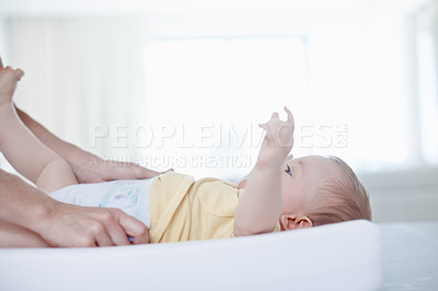 Buy stock photo A cute baby boy looking up at his mother as she changes his diaper