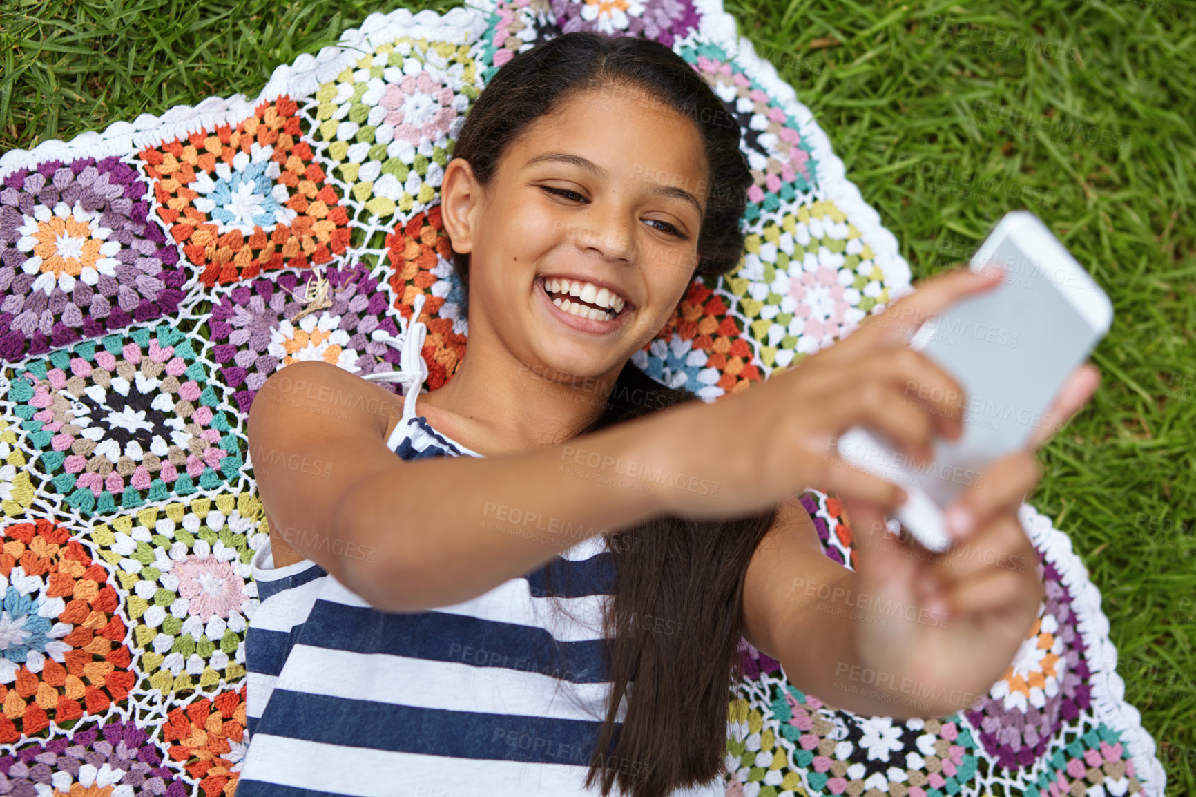 Buy stock photo Shot of a young girl taking a selfie while lying on a blanket in the outdoors