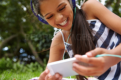 Buy stock photo Shot of a young girl listening to music on her cellphone in the outdoors