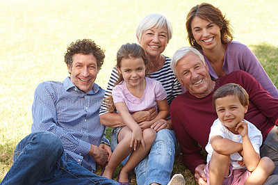 Buy stock photo Portrait of a happy multi-generational family sitting together on the grass outside