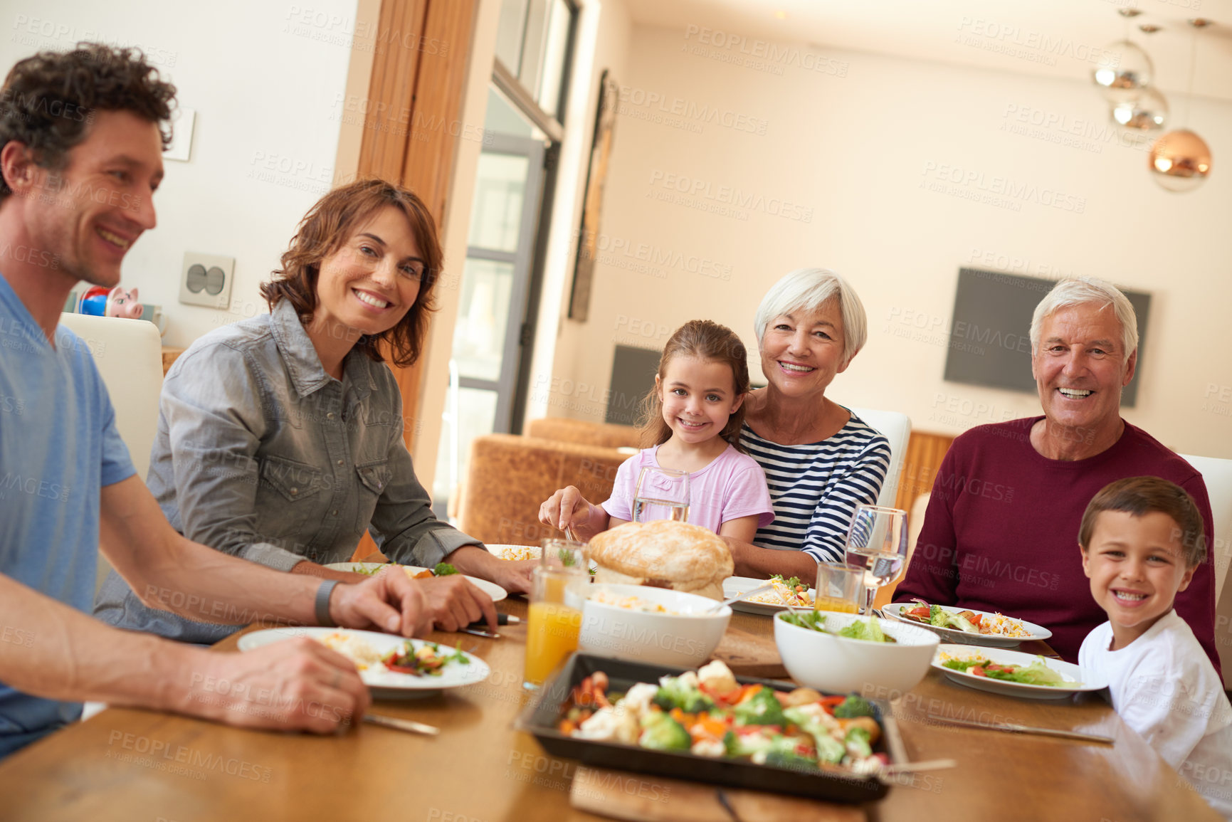 Buy stock photo Shot of a multi generational family having a meal together around a dining table