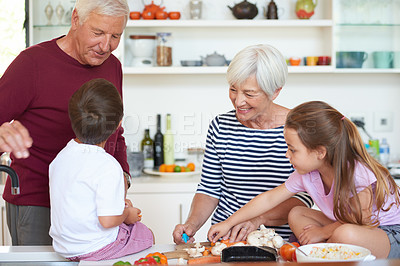 Buy stock photo Shot of grandparents preparing dinner with their grandchildren in a kitchen