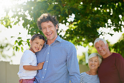 Buy stock photo Cropped portrait of a man holding his son outside with his parents in the background