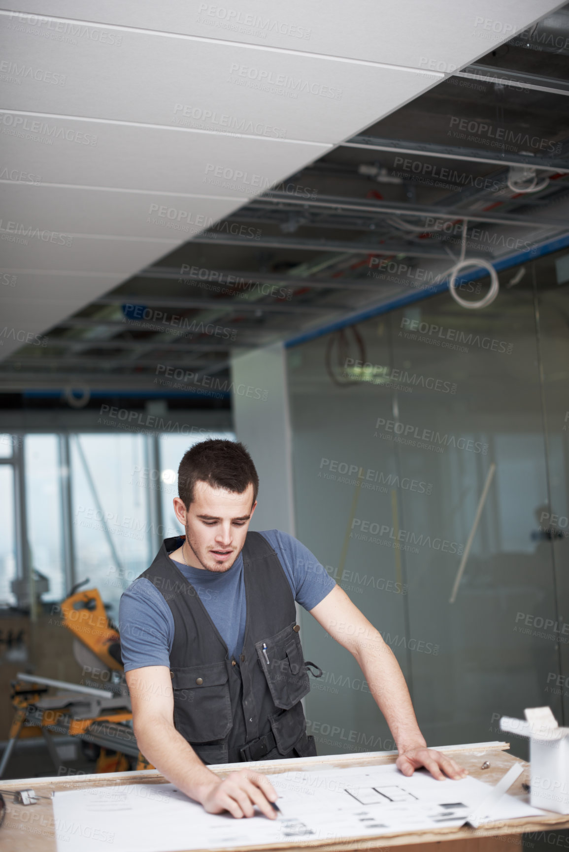 Buy stock photo Young architect working on his plans while at a construction site