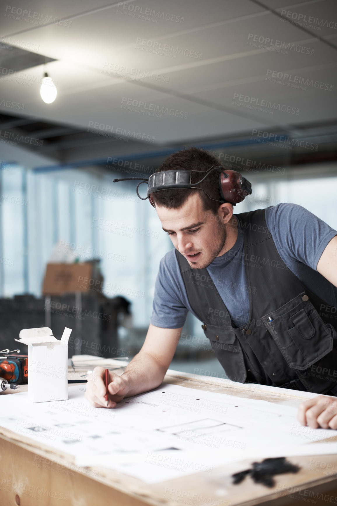 Buy stock photo Young architect working on his plans while at a construction site