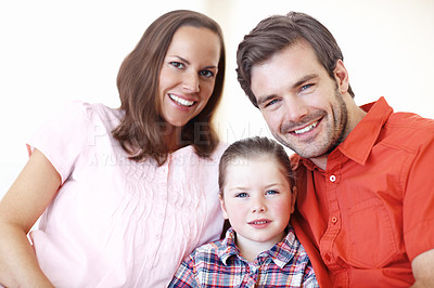 Buy stock photo Portrait of proud parents sitting with their daughter on the sofa