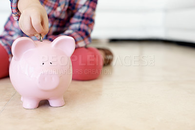 Buy stock photo Horizontal shot of a little girl's hand putting coins in a piggybank. Future savings. Securing future. Money saved is money earned.
 