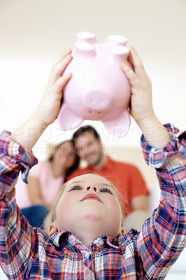 Buy stock photo A little girl holds her piggybak upside down