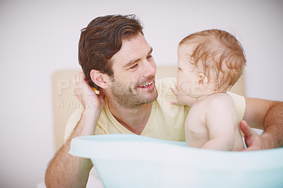 Buy stock photo A young father looking at his daughter with fondness as she sits in the bathtub