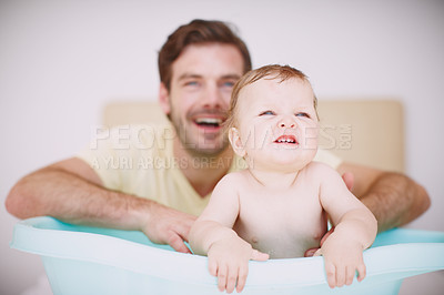 Buy stock photo A baby girl sitting in the bathtub with her father in the background
