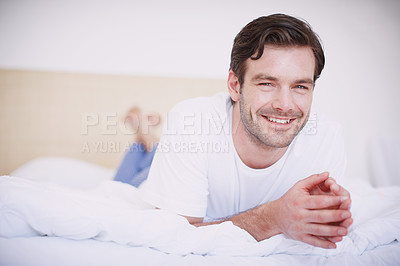 Buy stock photo Shot of a handsome young man relaxing on a bed