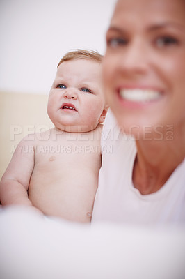 Buy stock photo Shot of a baby girl making a face while sitting next to her mother