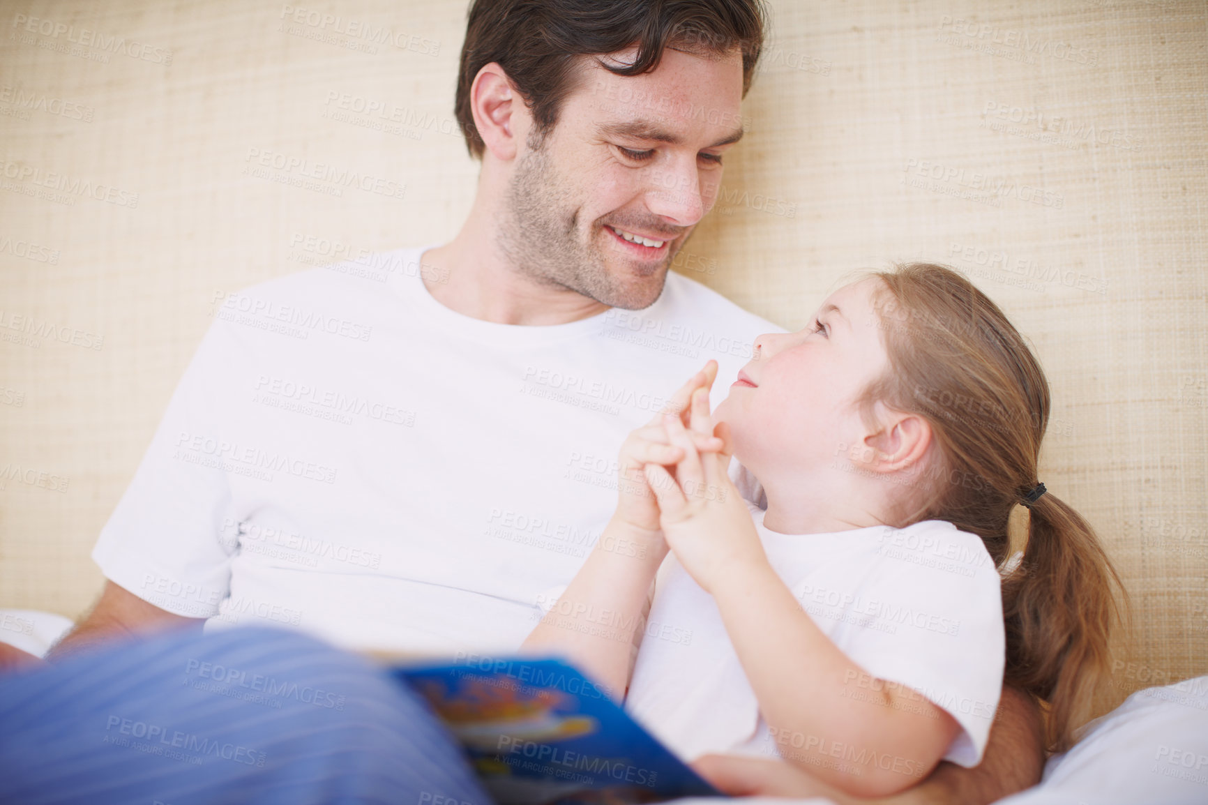 Buy stock photo A devoted father reading his young daughter a bedtime story