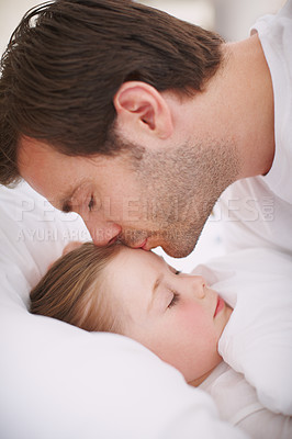 Buy stock photo Closeup shot of a dad putting his daughter to bed and kissing her on the forehead