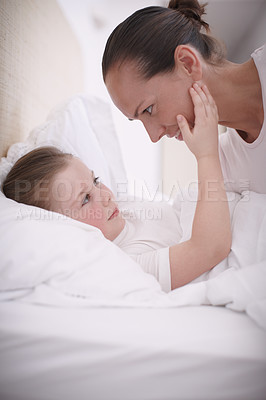 Buy stock photo A mom putting her young daughter to bed