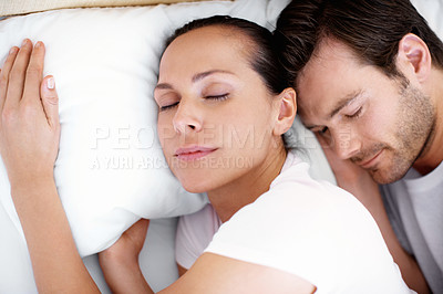 Buy stock photo A young couple lying in bed and cuddling