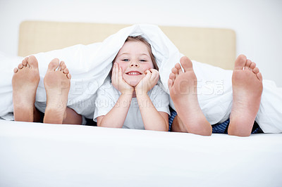Buy stock photo Fun shot of a child liying at the end of a bed between her parents feet