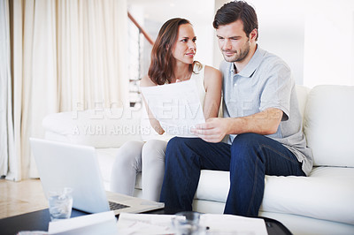 Buy stock photo A young couple discussing their finances while sitting together in their living room