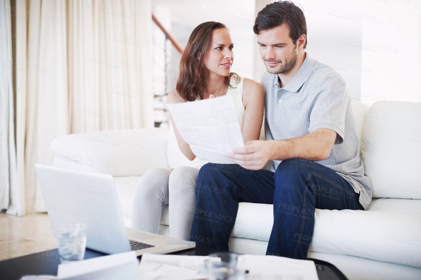 Buy stock photo A young couple discussing their finances while sitting together in their living room