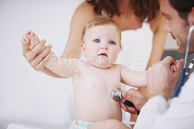 Buy stock photo A baby girl being examined by a doctor while her mother stands in the background