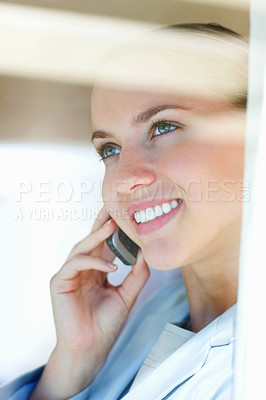 Buy stock photo Closeup of a happy female having a conversation over the cellphone , view through a glass