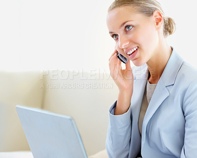 Buy stock photo Smiling young business woman speaking on the cellphone and using a laptop