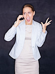 Angry business woman screaming over mobile phone against black