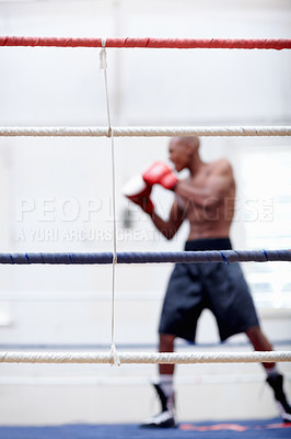 Buy stock photo African American male boxer practicing with boxing gloves in ring