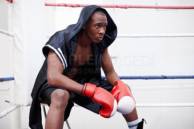 Buy stock photo African American male boxer in black hooded robe sitting in ring
