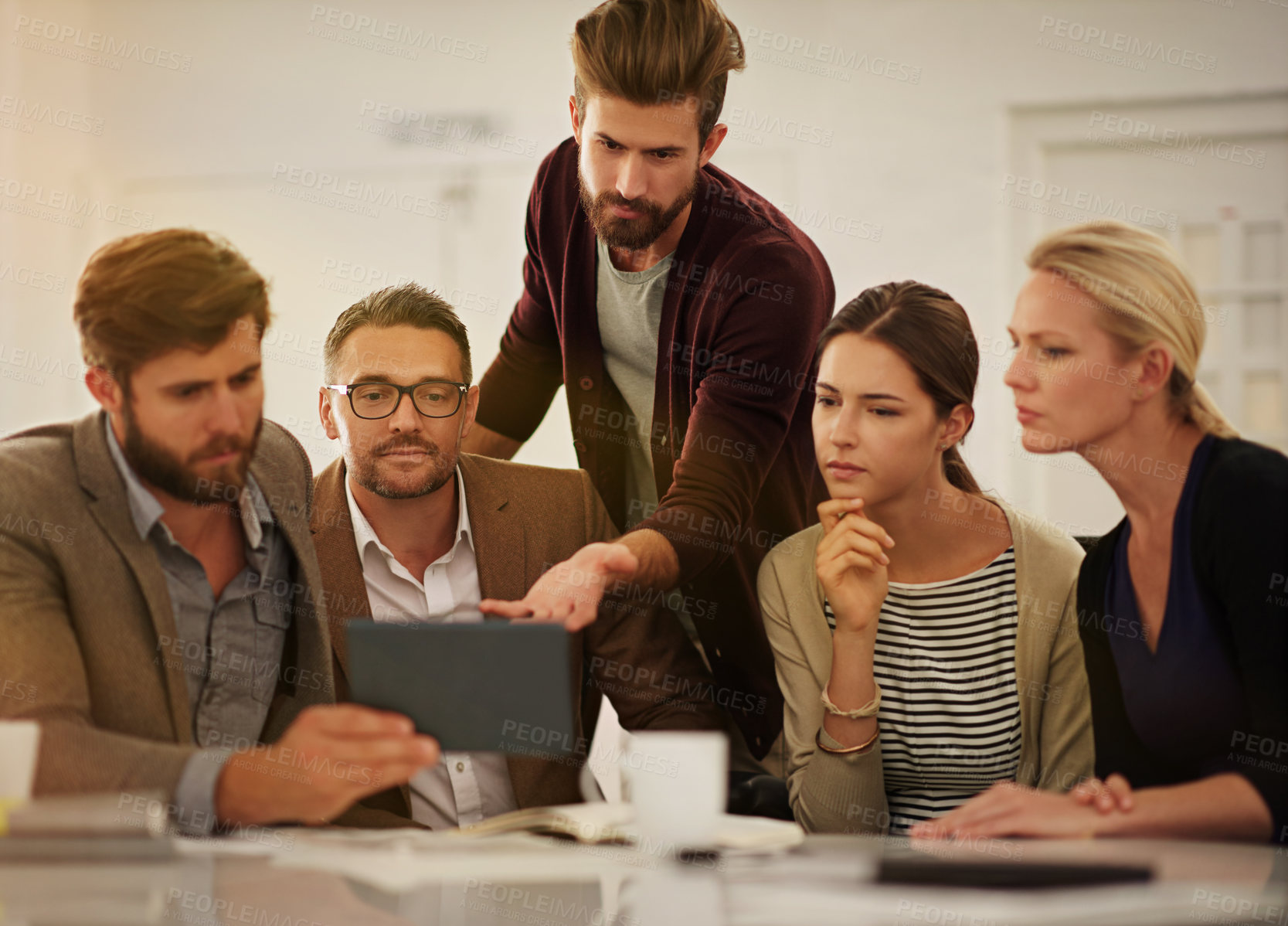 Buy stock photo Cropped shot of a group of businesspeople looking at a tablet in the boardroom