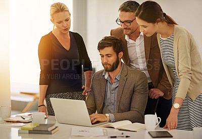 Buy stock photo Cropped shot of a group of businesspeople looking at a laptop in the boardroom