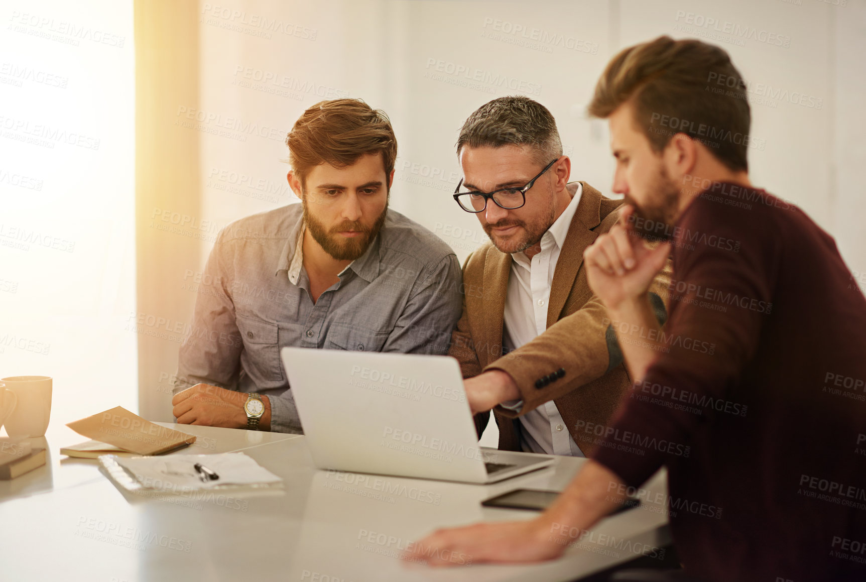 Buy stock photo Cropped shot of three businessmen looking at a laptop in the boardroom