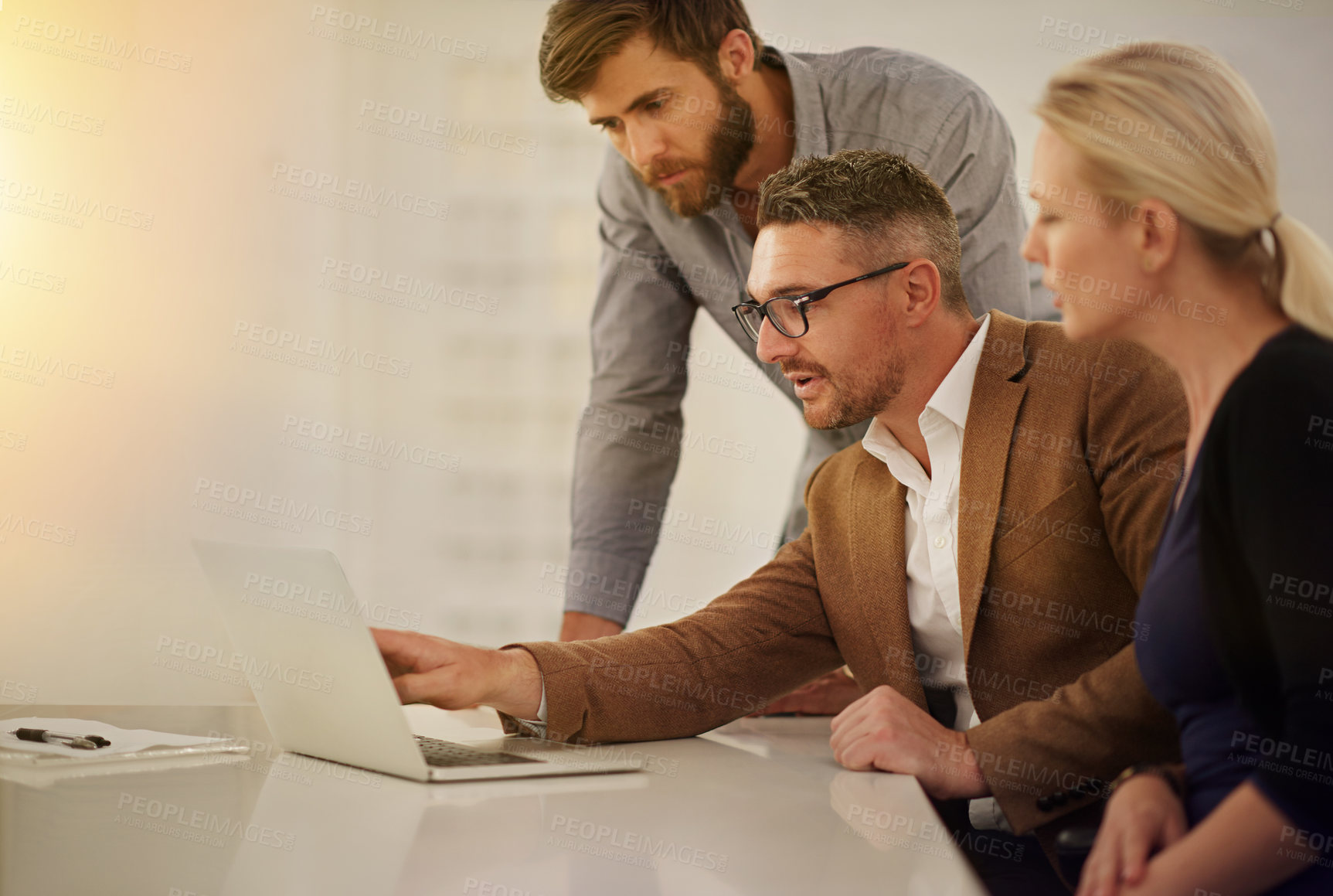 Buy stock photo Cropped shot of three businesspeople looking at a laptop in the boardroom