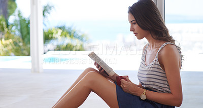 Buy stock photo Cropped shot of a young woman reading a book at home