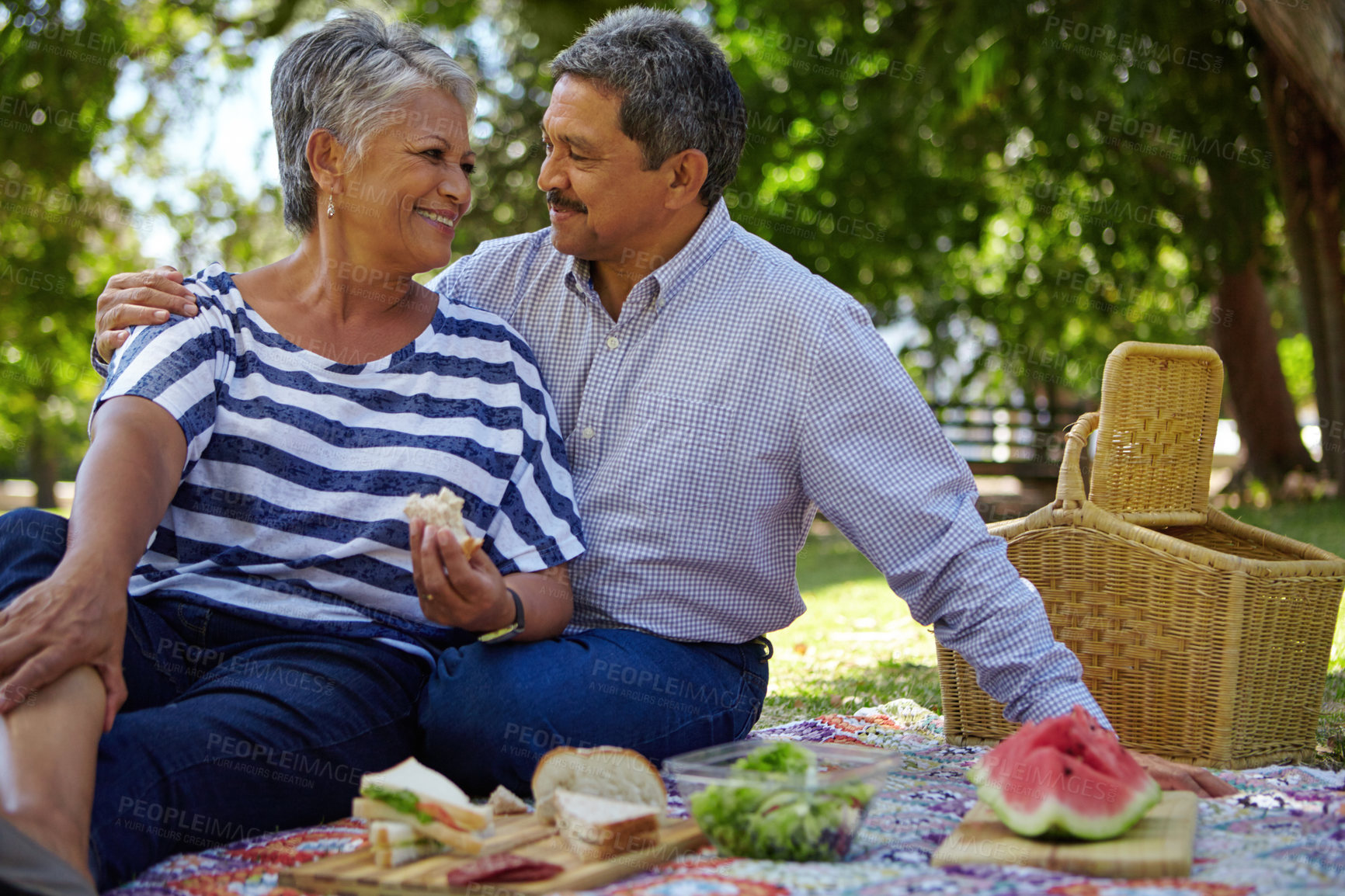 Buy stock photo Picnic, sandwiches and senior couple relax at park for anniversary, healthy lunch and bonding. Retirement, food and old people with romantic date outdoor for marriage trust, love and support with hug