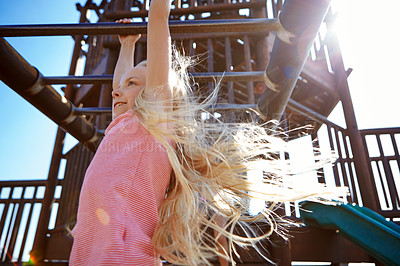 Buy stock photo Shot of a little girl hanging on the monkey bars at the playground