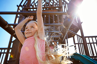 Buy stock photo Shot of a little girl hanging on the monkey bars at the playground