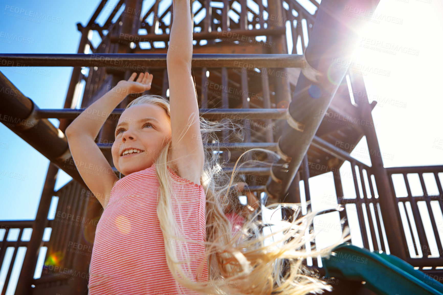 Buy stock photo Shot of a little girl hanging on the monkey bars at the playground