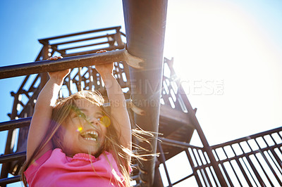 Buy stock photo Shot of a little girl hanging on the monkey bars at the playground