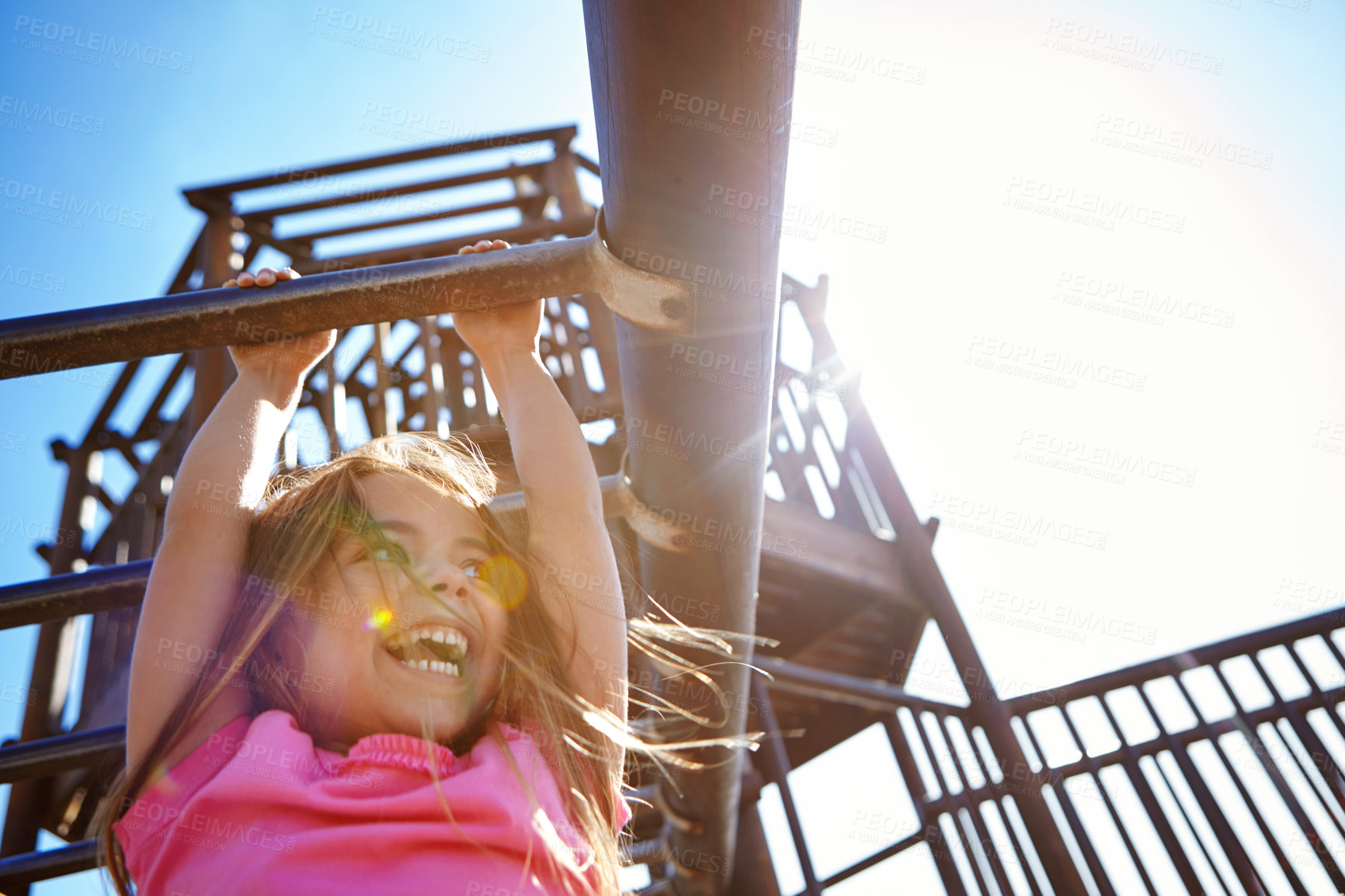 Buy stock photo Shot of a little girl hanging on the monkey bars at the playground