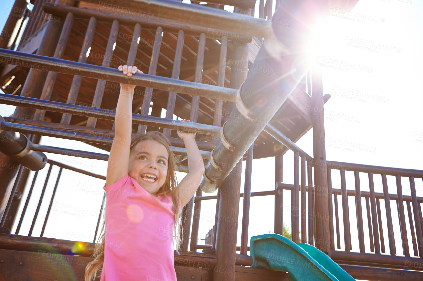 Buy stock photo Shot of a little girl hanging on the monkey bars at the playground