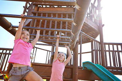 Buy stock photo Shot of two little girls hanging on the monkey bars at the playground